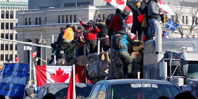 BESTANDSFOTO: Demonstranten staan ​​op een aanhanger met boomstammen terwijl vrachtwagenchauffeurs en supporters deelnemen aan een konvooi om te protesteren tegen de mandaten voor een coronavirus (COVID-19) vaccin voor grensoverschrijdende vrachtwagenchauffeurs in Ottawa, Ontario, Canada, 29 januari 2022. REUTERS/PATRICK DOYLE/BESTAND Foto