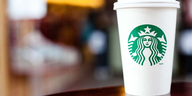 "Halifax, Nova Scotia, Anada - 18 september 2011: Grande Starbucks gaat voor een kopje aan een tafel.  Starbucks is een enorm populaire internationale coffeeshopfranchise met meer dan 15.000 locaties in 50 landen"