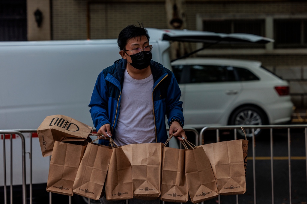 Een bezorger brengt eten naar een afgesloten woongemeenschap in Shanghai, China, 23 april 2022.