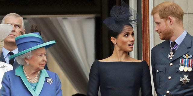 Koningin Elizabeth, Meghan Markle en prins Harry staan ​​op een balkon om in 2018 een RAF over Buckingham Palace te zien vliegen.