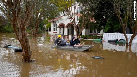 Mensen peddelen op een overstroomde straat in Windsor, Australië, 5 juli 2022