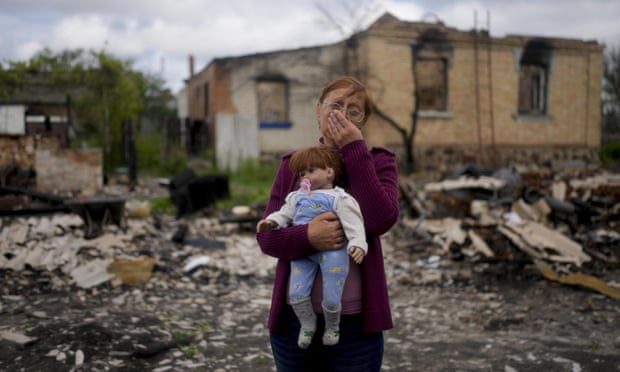 Nella Zelenska houdt een pop van haar kleindochter vast voor haar verwoeste huis in Potashnya, buiten Kiev, Oekraïne, in mei.