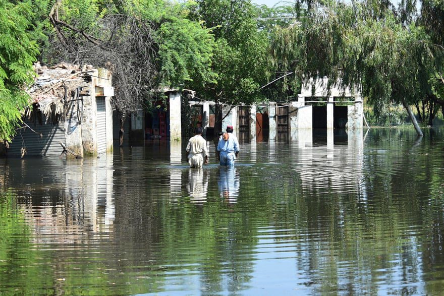 Bewoners waden in overstromingswater in de buurt van hun huizen na zware moessonregens.
