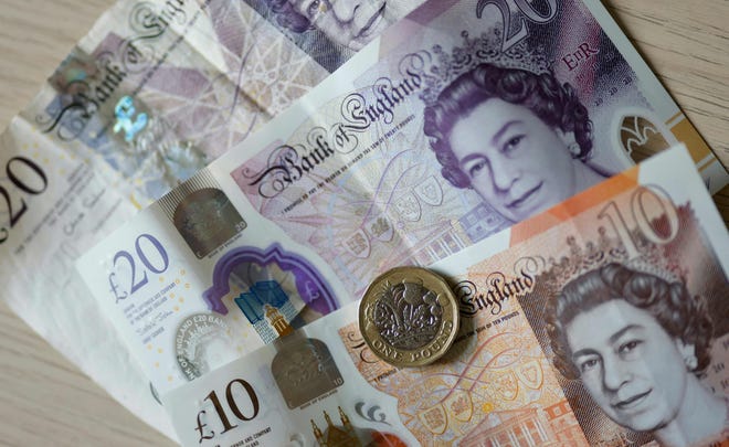 Een bestandsfoto gemaakt op 22 april 2022 toont biljetten en munten van Britse ponden op een tafel in Londen.  De bankbiljetten zouden uiteindelijk veranderen na de dood van koningin Elizabeth II.