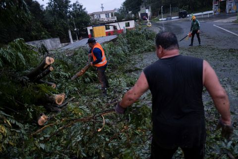 Mensen hebben zondag een pad vrijgemaakt van een omgevallen boom in Yaoco, Puerto Rico.