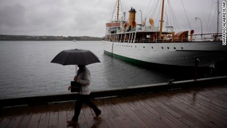 Een voetganger beschermt zichzelf met een paraplu tijdens een wandeling langs de waterkant van Halifax met regen voordat orkaan Fiona aan land komt in Halifax, vrijdag 23 september 2022.