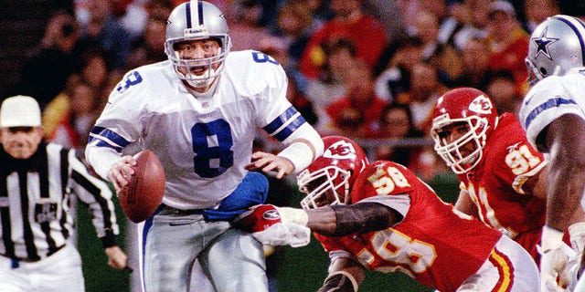 Dallas Cowboys quarterback Troy Aikman staat op het punt te worden ontslagen door Kansas City Chiefs quarterback Derek Thomas (rechts) in Kansas City.