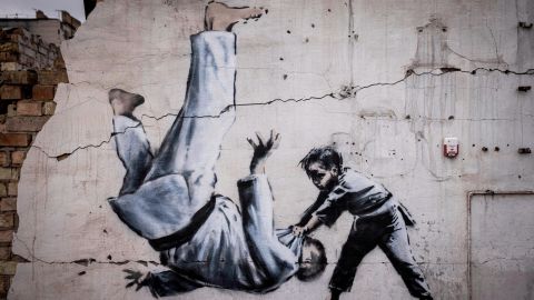 Een muurschildering die Banksy niet officieel heeft geclaimd, toont een man die zich omdraait tijdens een judowedstrijd met een jongen. 