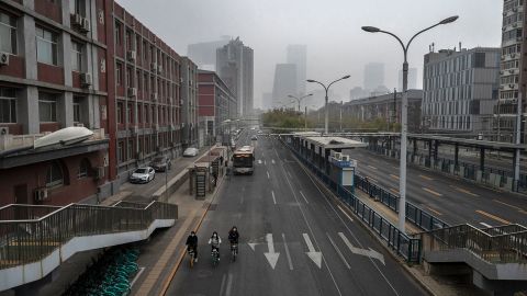 Mensen fietsen op 24 november in een lege straat in de buurt van het centrale zakendistrict in Peking. 